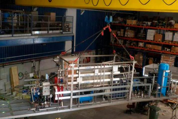 Maquinaria industrial suspendida por grúa en almacén