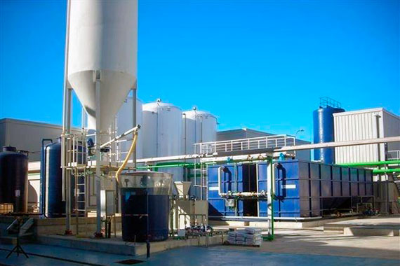 Instalación industrial con tanques y tuberías bajo cielo azul
