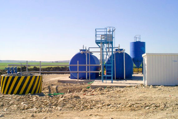 Depósitos industriales azules en entorno rural
