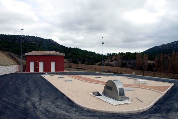 Instalación industrial con edificio rojo y colinas