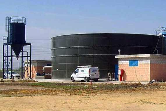 Depósito industrial con tanque y furgoneta blanca