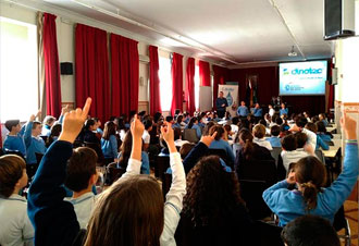 Estudiantes levantan la mano en una charla escolar