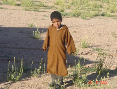 Niño con túnica marrón en paisaje árido
