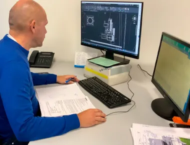 Hombre trabajando en ordenador con planos técnicos