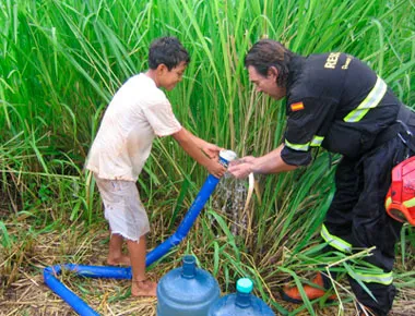 Bombero ayudando a niño con manguera en campo